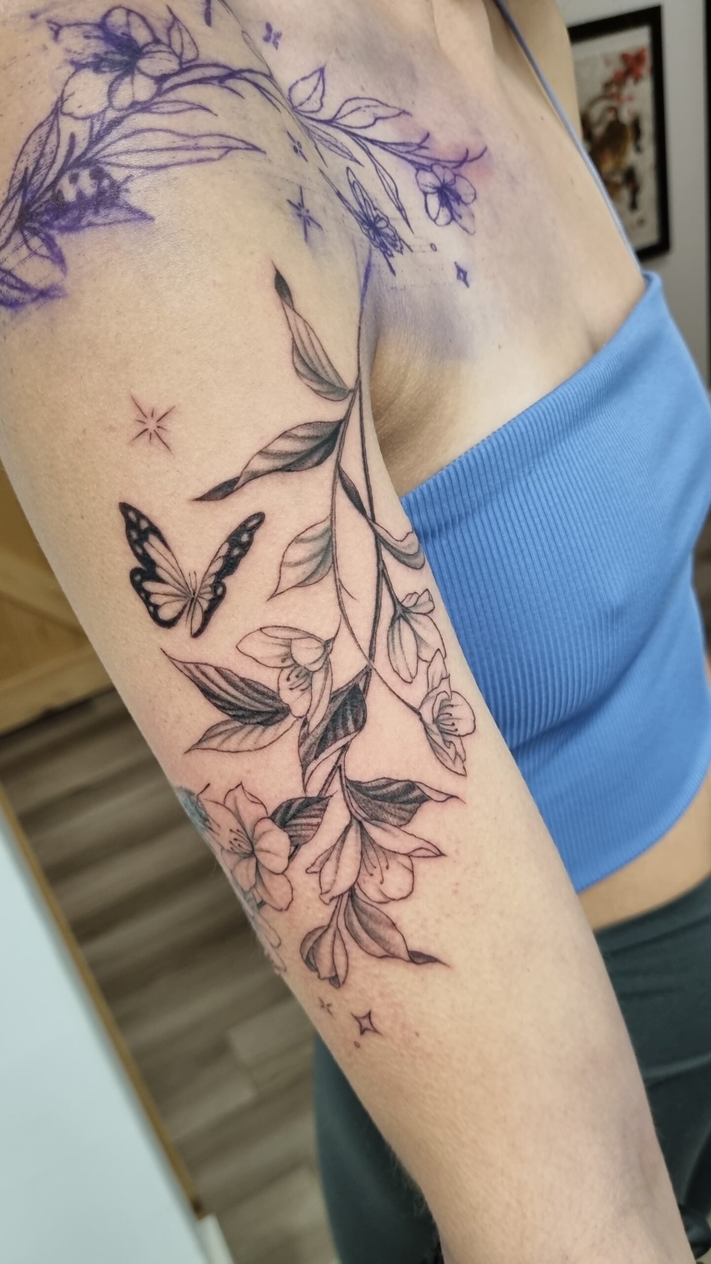 black and grey flower butterfly realism tattoo on upper outer arm by nat what i tat at 7th house tattoo fredericton new brunswick canada