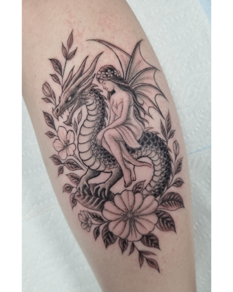 13 Storybook illustration tattoo of a fairy riding a dragon framed by wildflowers.